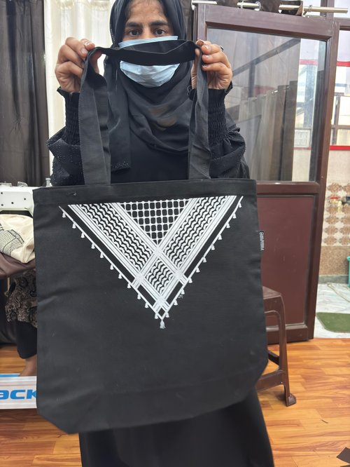 A trainee displays a handmade bag featuring the Palestine logo, one of the products sold on Sabaat’s online marketplace.