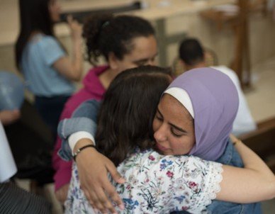 Two young ladies from Balansura greeting each other after the workshop inside the church hall